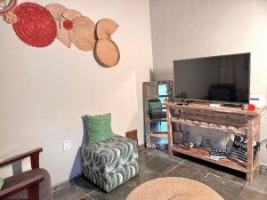 a living room with a tv and a chair at Refúgio em Lumiar com Piscina, Churrasqueira e Natureza ao Redor in Nova Friburgo