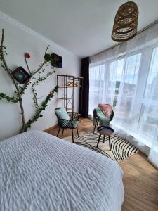 a bedroom with a bed and two chairs and windows at L'Eden - Premium Suite - Vue - Balcon in Lourdes +27 photos
