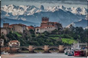 a town on a hill with a bridge and mountains at Apartamento La Gaviota A estrenar in San Vicente de la Barquera