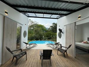 a room with chairs and a bed and a pool at Hermosa cabaña en Villeta in Villeta