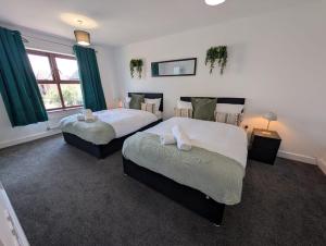 two beds in a room with green curtains at Spacious Large 4 Bed Contractor in Dallington