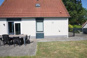 a patio with a table and chairs and a building at Kustverhuur Park Schoneveld Stern 228, gerenoveerd april 2025 in Breskens
