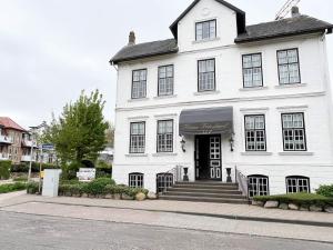 un edificio blanco con una puerta negra en una calle en Haus Friesland - Wohnung 5, en Westerland