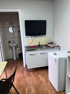a kitchen with a sink and a tv on the wall at Kitinete perto da Itaipu e Unioeste in Foz do Iguaçu