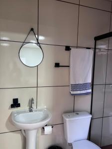 a bathroom with a sink and a toilet and a mirror at Kitinete perto da Itaipu e Unioeste in Foz do Iguaçu