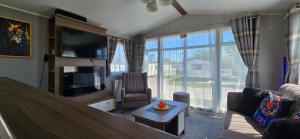 a living room with a large window and a living room with a television at RJ Luxury Caravan Hire With Hot Tub in Tattershall