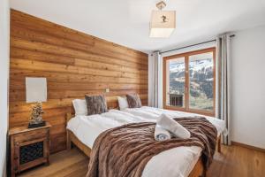 a bedroom with a large bed with a wooden wall at Chalet White Peak by Miggins in Grimentz +11 photos