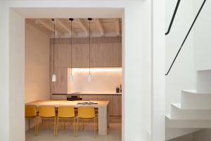 a kitchen with a wooden table and yellow chairs at Unika Homes Casa Bella in Seville