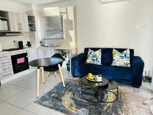 a living room with a blue couch and a table at Cozy One-bedroom Apartment near GrandPalm Resort Block 5, Gaborone, Botswana in Mogoditshane