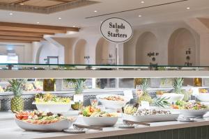a buffet line with bowls of salads and strawberries at Atlantica Aeneas Resort in Ayia Napa