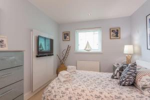 a bedroom with a bed and a tv on the wall at Sail Away - Luxury Apartment with Stunning Harbour Views in Poole