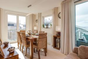 a dining room with a table and chairs and windows at Sail Away - Luxury Apartment with Stunning Harbour Views in Poole