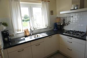 a kitchen with a sink and a stove at Kustverhuur, Nieuwesluisweg 6A in Breskens