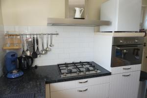 a kitchen with a stove and white cabinets at Kustverhuur, Nieuwesluisweg 6A in Breskens +14 photos