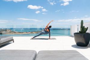 a woman doing a yoga pose on top of a building at Blue Marina Suites - Boutique Apartments in Arrecife