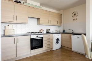a kitchen with wooden cabinets and a washer and dryer at Ahoy - Balcony with Beautiful Harbour Views in Poole