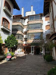 Un gran edificio blanco con un patio delante. en Apartamento a 200 metros da Rua Coberta, en Gramado