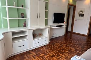 a living room with white cabinets and a television at Apto central na Via Del Vino in Bento Gonçalves