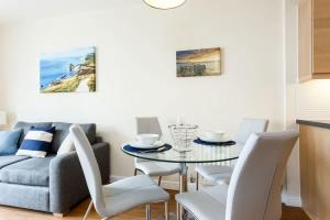 a living room with a glass table and white chairs at Coxswain's Cabin - Moments from Hamworthy Beach and Park in Poole