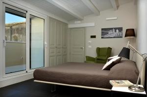 a bedroom with a bed and a chair and a window at B&B Vicere Speciale in Noto