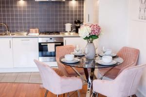 a kitchen with a table with chairs and a vase of flowers at Mojo - Modern Apartment with Balcony in Poole