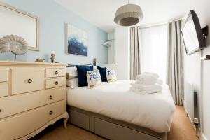 a bedroom with a white bed and a dresser at Mojo - Modern Apartment with Balcony in Poole