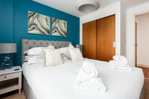 a bedroom with a white bed with blue walls at Mojo - Modern Apartment with Balcony in Poole
