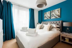 a bedroom with a large bed with blue walls at Mojo - Modern Apartment with Balcony in Poole
