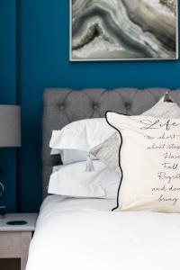 a bed with white pillows and a blue wall at Mojo - Modern Apartment with Balcony in Poole