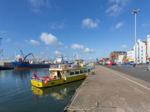 a yellow boat in the water next to a dock at Mojo - Modern Apartment with Balcony in Poole