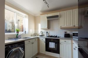 een keuken met witte kasten, een wasmachine en een raam bij Palma - Hamworthy Beach and Park Short Walk Away in Poole