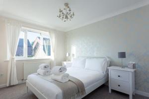 een slaapkamer met een wit bed en handdoeken bij Palma - Hamworthy Beach and Park Short Walk Away in Poole