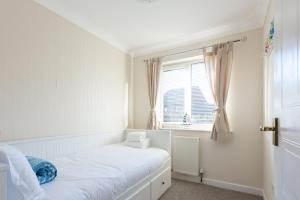 een witte slaapkamer met een bed en een raam bij Palma - Hamworthy Beach and Park Short Walk Away in Poole +9 foto's