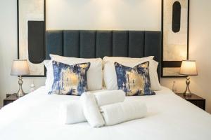 ein Schlafzimmer mit einem weißen Bett mit blauen und weißen Kissen in der Unterkunft Stylish 3BD Flat in Prime Covent Garden Location in London