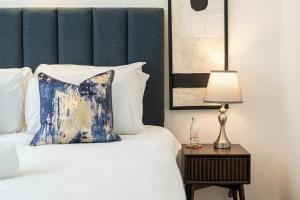 Schlafzimmer mit einem Bett mit blauem Kopfteil und einer Lampe in der Unterkunft Stylish 3BD Flat in Prime Covent Garden Location in London