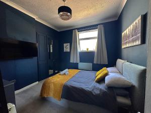 a blue bedroom with a bed and a window at Bournemouth's Hidden Garden Apartment in Bournemouth