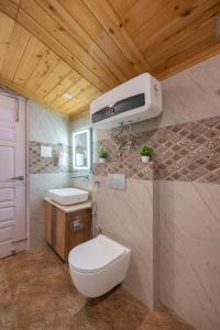 a bathroom with a toilet and a tv on the wall at Rad Retreat by High Rise Inn kufri in Kūfrī