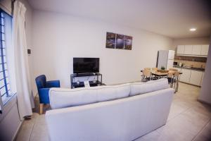 a living room with a white couch and a kitchen at Complejo Coirón in San Rafael