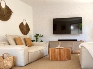 a living room with a white couch and a tv at La Maison d'Ambrine - Villa Grignan in Grignan