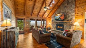 a living room with two couches and a stone fireplace at Cozy Black Bear Cabin porch swing & stunning views in Sevierville