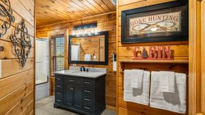 a log cabin bathroom with a sink and a mirror at Cozy Black Bear Cabin porch swing & stunning views in Sevierville +22 photos