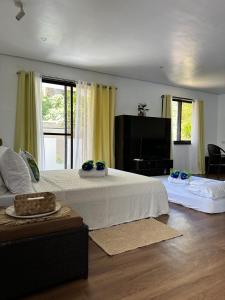 a bedroom with a white bed and a television at Kawayan Terrace - Boracay in Boracay