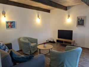 un soggiorno con sedie e TV a schermo piatto di Gîte The Butterfly - 1 bedroom and mezzanine a Monteux