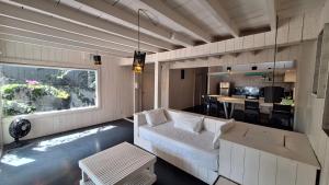 a living room with a white couch and a kitchen at As Palhas in Icaraí