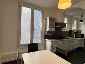 a kitchen with a table and two windows and a counter at App centre-ville près du château, grand appartement in Caen