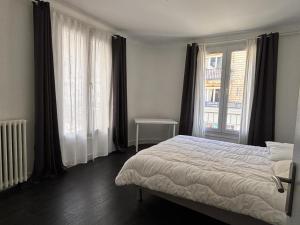 a bedroom with a bed and two large windows at App centre-ville près du château, grand appartement in Caen