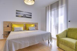 a bedroom with a bed with yellow pillows and a chair at Apartment Falu in Štinjan +14 photos