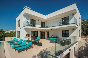 a white house with blue chairs on a patio at Villa Sail in Pješčana Uvala 