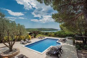 a swimming pool with chairs and a view of the water at Villa Mima in Banjole