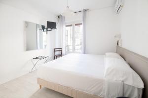 una camera da letto bianca con un letto grande e una sedia di Hotel Europa ad Arma di Taggia